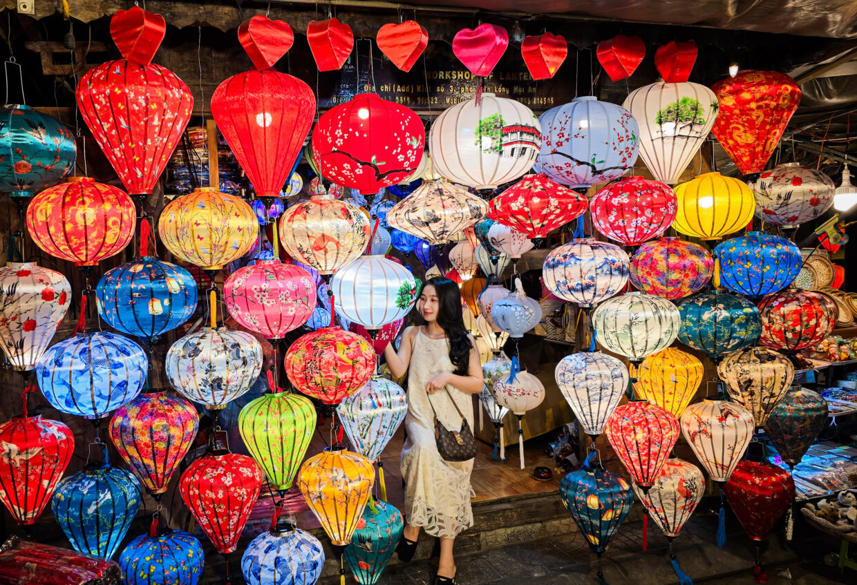 A young Vietnamese woman stands among colorful illuminated lanterns